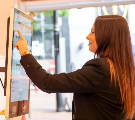 Guest ordering at a Kate One kiosk by a shop front